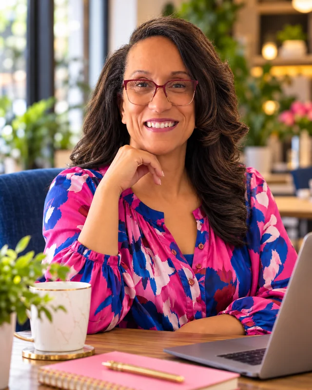 Petrina Palmer smiling at a table with a laptop and notebook